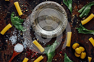 Top view of table with italian tortiglioni pasta, metal plate and spices.