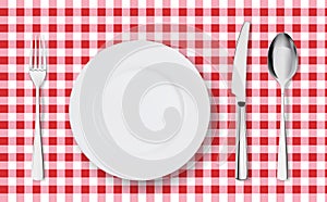 Top view of table place setting for dinner on red tablecloth with empty plate glasses and cutlery.