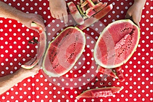 Top view of table and polka dots tablecloth on it.People eating ripe watermelon