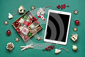 top view tablet with black digital screen, Christmas box and decor on green table Flat lay Holiday shopping list, Happy