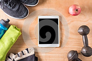 Top view of Tablet with Sport stuff on wooden table background,