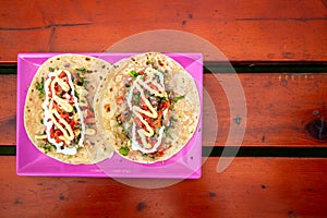 Top View of Tacos. Handmade Mexican food served in a pink plate placed on a wooden surface. Authentic Spicy Food