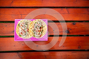Top View of Tacos. Handmade Mexican food served in a pink plate placed on a wooden surface. Authentic Spicy Food