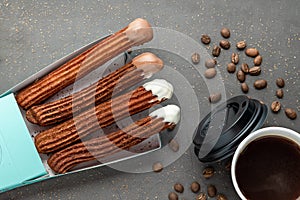 Top view of take away coffee next to chocolate filled and plain churros