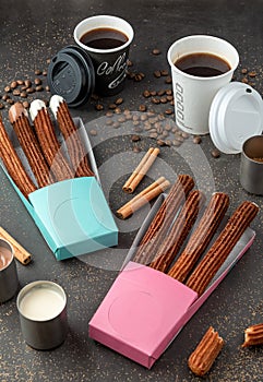 Top view of take away coffee next to chocolate filled and plain churros