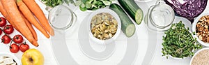 Top view of tasty fruits and vegetables in bowls near glass jars on wooden white table with copy space, panoramic shot.