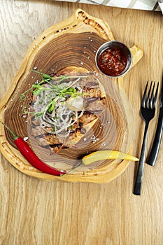 Top view tasty Grilled Pork neck served on pita bread with onion, microgreen and hot pepper. Wooden background. Copy space.