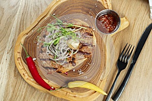 Top view tasty Grilled Pork neck served on pita bread with onion, microgreen and hot pepper. Wooden background. Copy space.