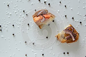 Top view of tasty Italian appetizers -  bruschetta with raw tomatoes and octopus tentacles, on slices of toasted baguette