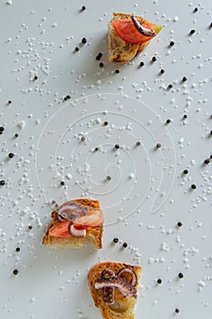 Top view of tasty Italian appetizers -  bruschetta with raw tomatoes and octopus tentacles, on slices of toasted baguette