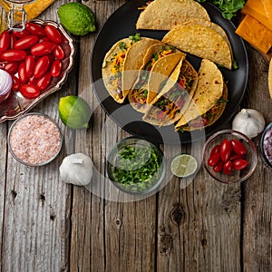 Top view of tasty mexican tacos with meat on black round plate on rustic wooden table. Traditional mexican cuisine. Healthy