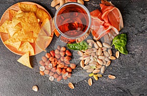 Top view of tasty snacks and dark beer on a table background. Peanuts, pistachios, prosciutto with a glass of beer. Cold