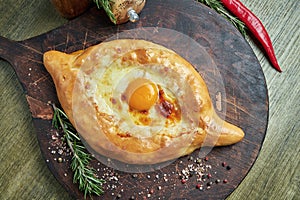 Top view on tasty traditional Adjarian Khachapuri - open baked pie with melted salt cheese suluguni and egg yolk on wooden tray