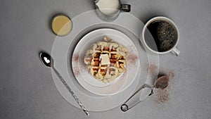 Top view of tasty Waffles Plate, Caramel Sauce, Coffee Cup, Milk, dessertspoon, strainer