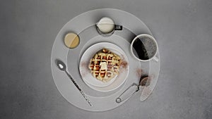 Top view of tasty Waffles Plate, Caramel Sauce, Coffee Cup, Milk, dessertspoon, strainer