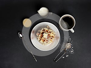 Top view of tasty Waffles Plate, Caramel Sauce, Coffee Cup, Milk, dessertspoon, strainer