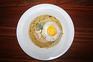 Top view tasty yellow rice plate with egg omelette, plums, mint leaf,lemon slice on white plate on wood table