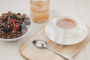 Top view of tea, honey and flakes with berries/top view of tea, honey and flakes with berries on a wooden background