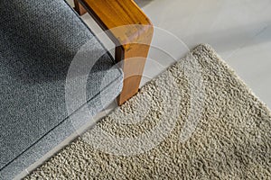 Top view of teak wood sofa edge on beige carpet.