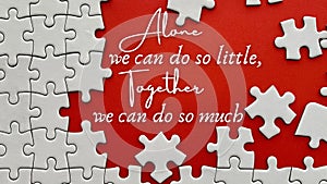 Top view of teamwork inspirational quote on red cover with jigsaw puzzle - Alone we can do so little, together we can do