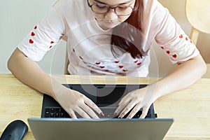 Top view of teen girl with laptop in her room while sitting at the desk and writing on her laptop