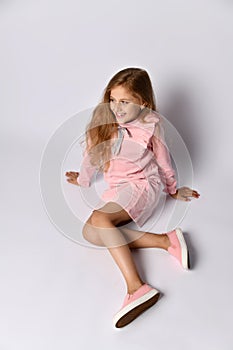 Top view of a teenager girl in a casual pink dress and gym shoes. The style of youth and adolescents. On a light background.