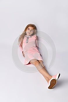 Top view of a teenager girl in a casual pink dress and gym shoes. The style of youth and adolescents. On a light background.