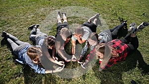 Top view teenagers in circle using phones in park