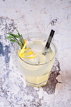 Top view tequila, lemon, rosemary fizz. Alcoholic drink in glasses with fresh herbs on a gray background, selective