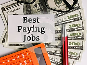 Top view text Best Paying Jobs written on white paper note with calculator,pen and eye glasses.