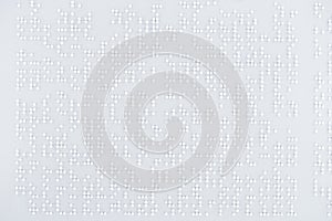 Top view of text in international braille code on white paper.