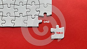 Top view of text - one team. On red background of white jigsaw missing pieces. Business concept.