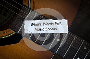 Top view of text on torn paper - Where words fail, music speaks with guitar background. Conceptual