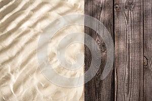 Top view of textured sand and wooden brown board with copy space.