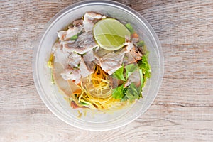 Top view Thai and China Asian food yellow noodles lemon lime, Dry noodles pork with red roasted pork and vegetable in plastic bowl