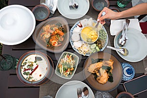 Top view of Thai food with salted crab, rice noodles, fried sea bass, sliced mango spicy, creamy chicken soup, vermicelli salad