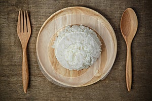 Top view of Thai jasmine rice in wooden dish with napery and wooden spoon - soft focus