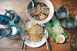 Top view thai street food on old wooden table padthai and guay jub noodle, popular traditional thai dish photo