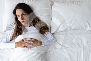 Top view thoughtful woman lying in empty bed alone