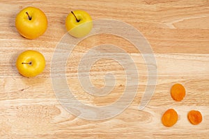 Top view of three apples and dried apricots with copyspace on a wooden table