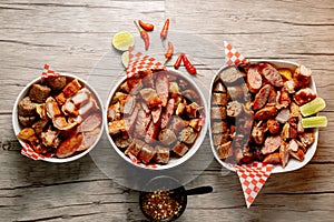 Top view of three bowls of different sliced meats and a bowl of vegetable soup on the side