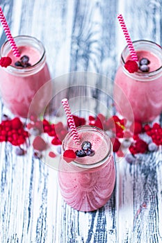 Top view of three jars with yogurt smoothie with cranberry, raspberry, blueberry on wooden table