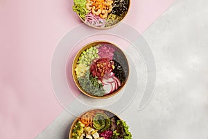 Top view of three plates full of diet dishes on a grey and pink background- vegan food concept