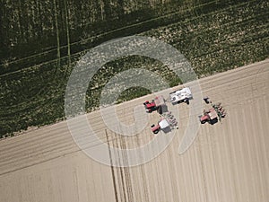 Top view of Three red tractors are preparing to fertilize the field