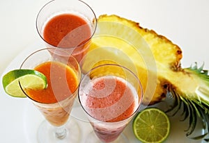 Top view of three smoothies, a pineapple, and a lime slice