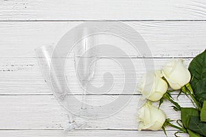 Top view of three White roses and two champagne glasses on old white wooden table love concept