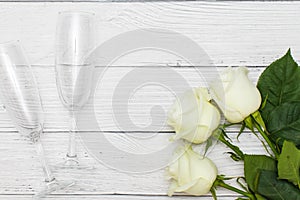 Top view of three White roses and two champagne glasses on old white wooden table love concept