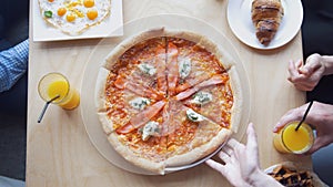 Top view - thw waiter brings the pizza for students in cafe