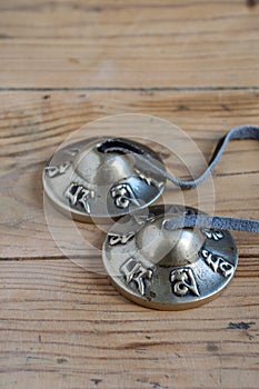 Top view of Tibetan cymbals on wooden table, vertical,