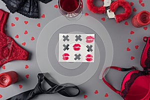 top view of tic-tac-toe game between underwear and glass of wine, valentines
